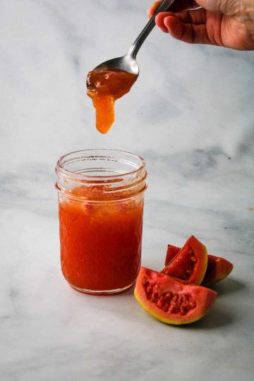 hand scooping guava jam with a spoon