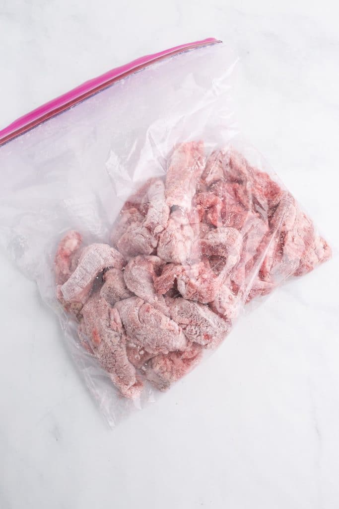 cut beef coated in flour in a zip top back