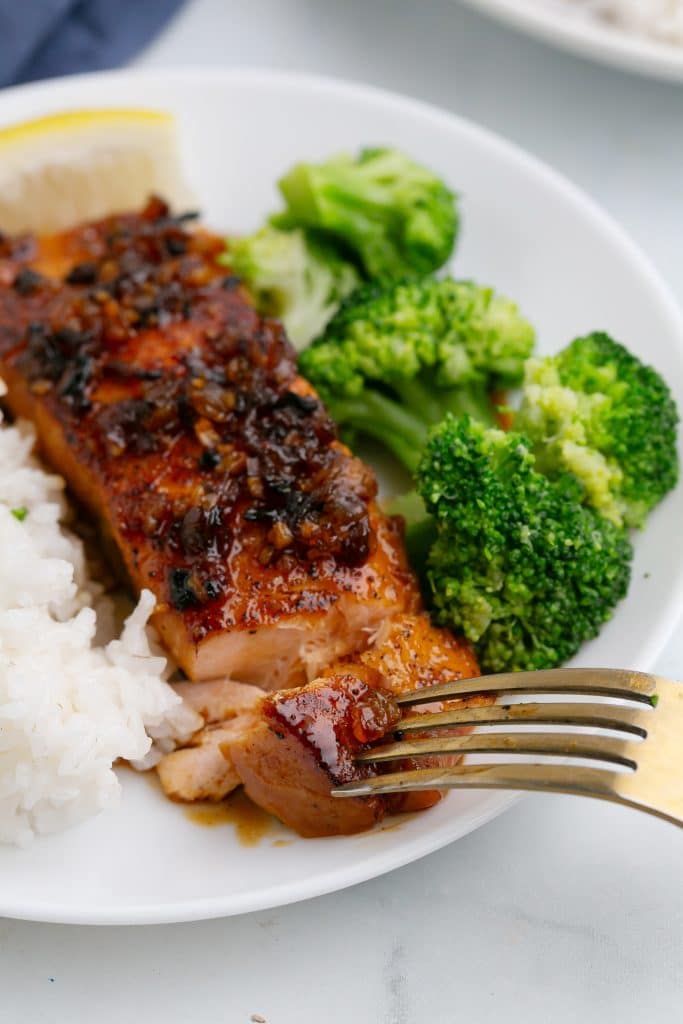 fork cutting a piece of honey garlic salmon