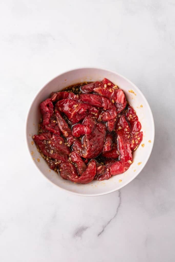 beef marinating in a white bowl